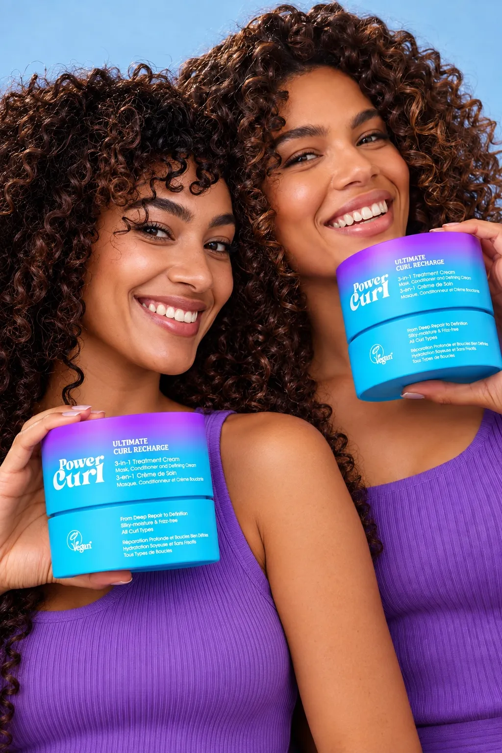 Two smiling women with curly hair holding jars of Power Curl Ultimate Curl Recharge